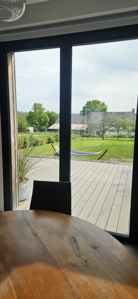 Baie vitrée propre donnant sur un jardin et une terrasse